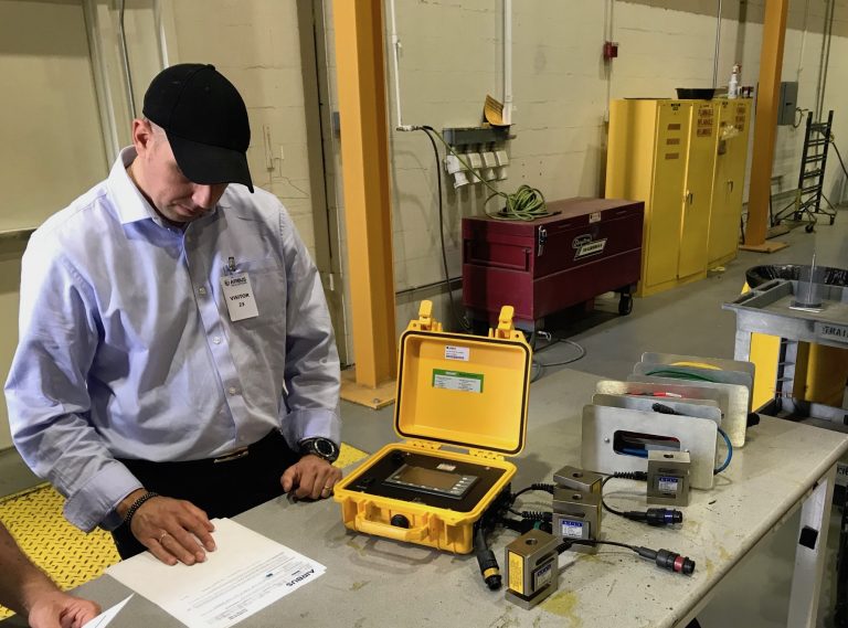 Technician looking at paperwork and preparing the helicopter weighing equipment, a yellow box with different coloured cables.